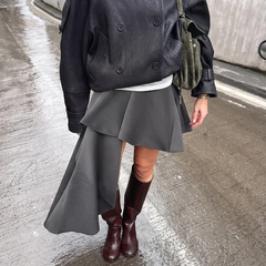 Full view of an asymmetrical high-waisted skirt with a draped hem.