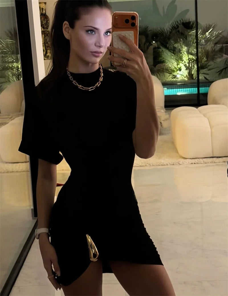 Woman taking a mirror selfie wearing a black dress in an indoor setting.