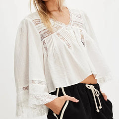 White lace top worn by a person on a white background