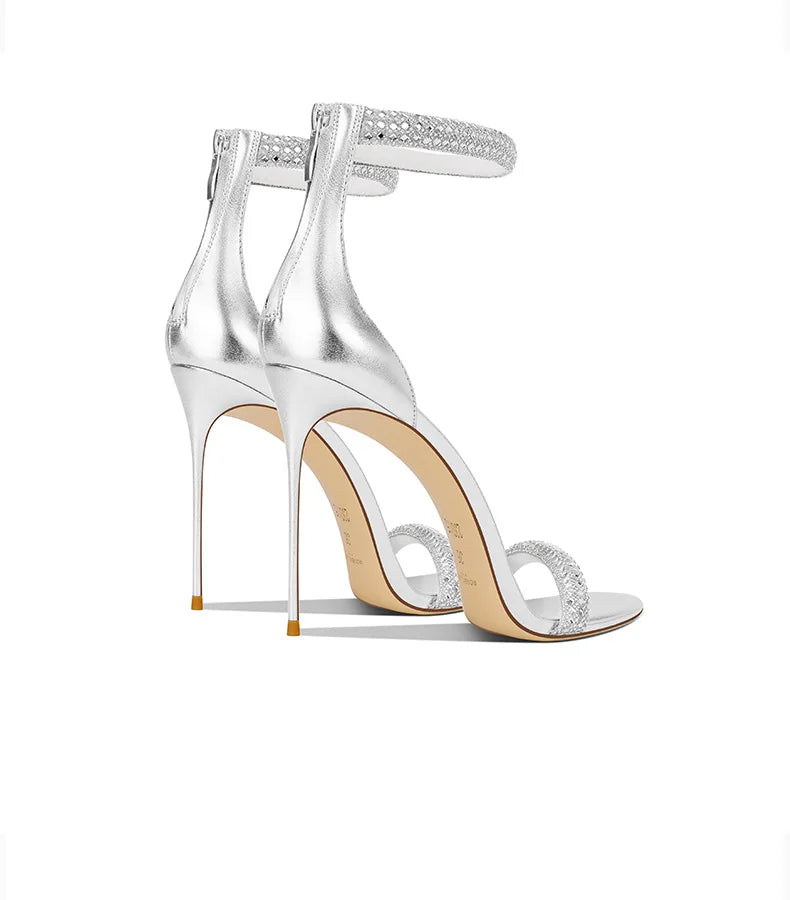 Silver high-heeled shoes with clear straps on a white background