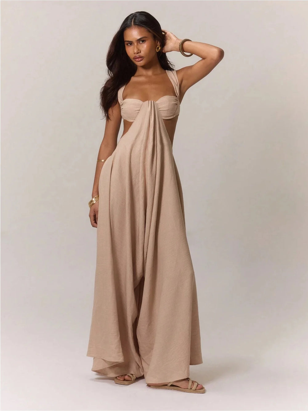 Woman wearing a beige strapless jumpsuit against a plain background