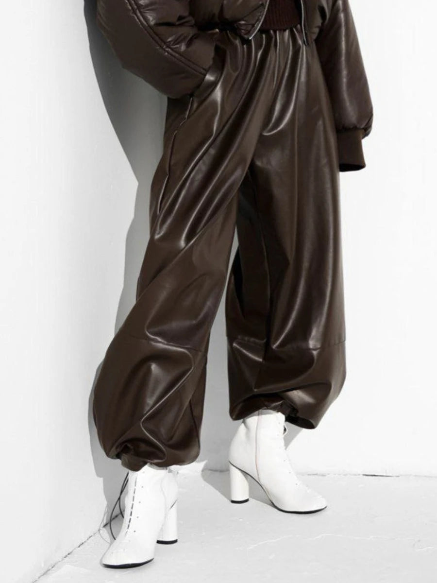Brown shiny pants worn by a person on a white background