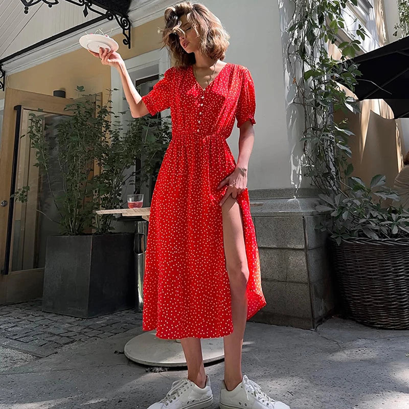 Woman in a red dress standing outdoors with plants and a building in the background