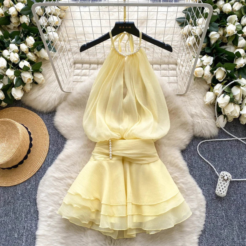 Yellow dress on a hanger with floral decorations and a hat in the background