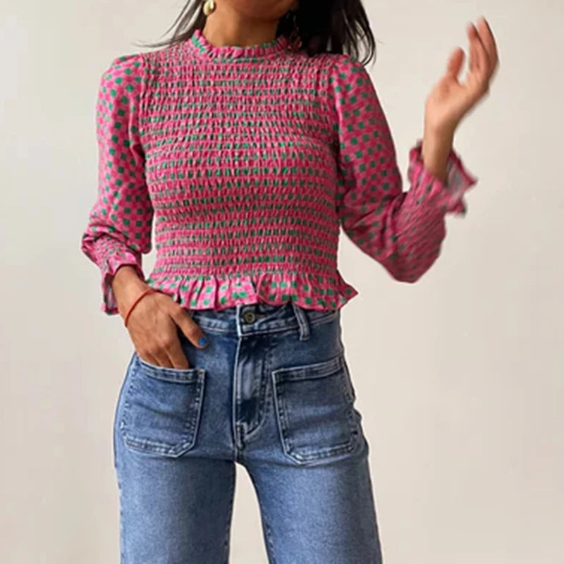 Person wearing a pink patterned blouse and blue jeans against a plain background