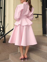 Person wearing a pink dress with ruffled layers, standing on steps.