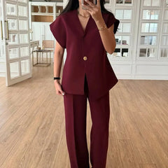 Person wearing a burgundy suit in a room with wooden flooring and large windows.