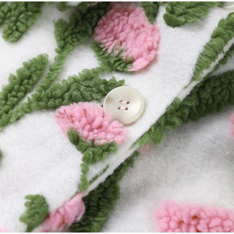 Close-up of a textured fabric with pink flowers and green leaves on a white background