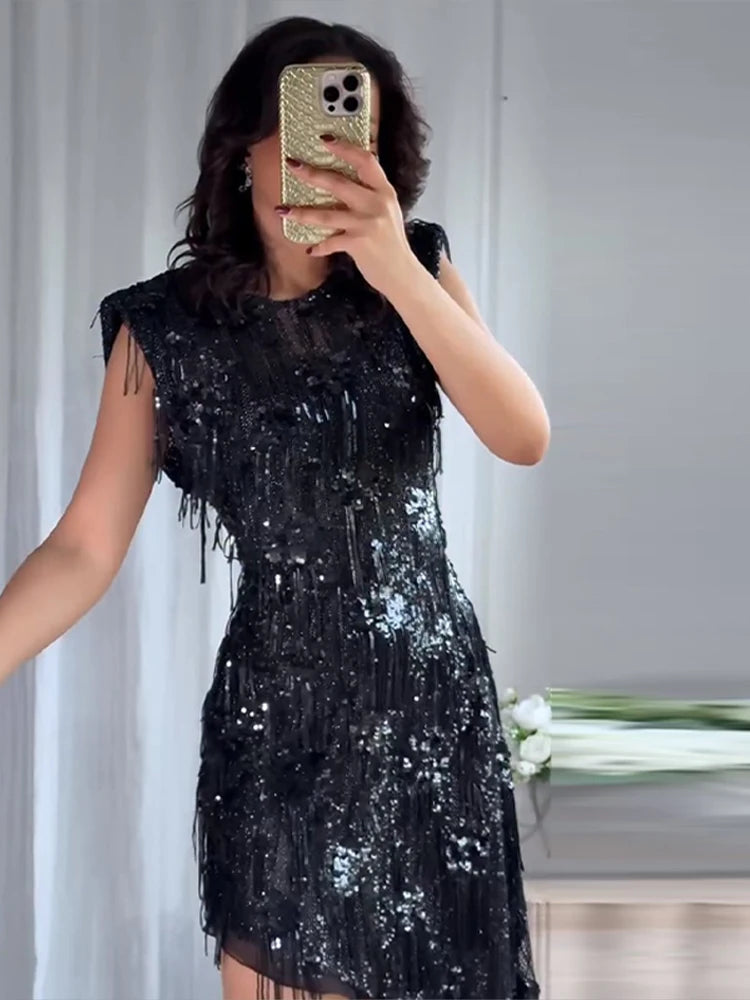 Person wearing a black sequin dress taking a mirror selfie.