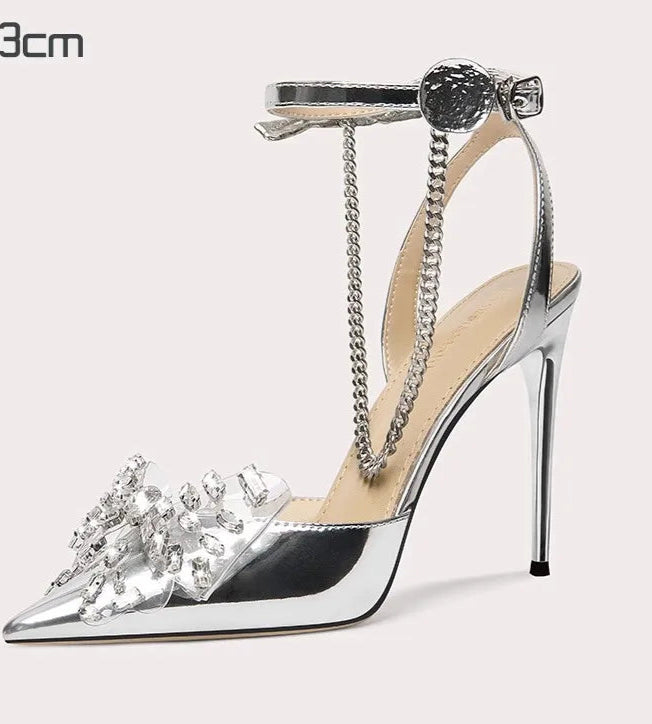 Silver high-heeled shoe with decorative elements on a white background