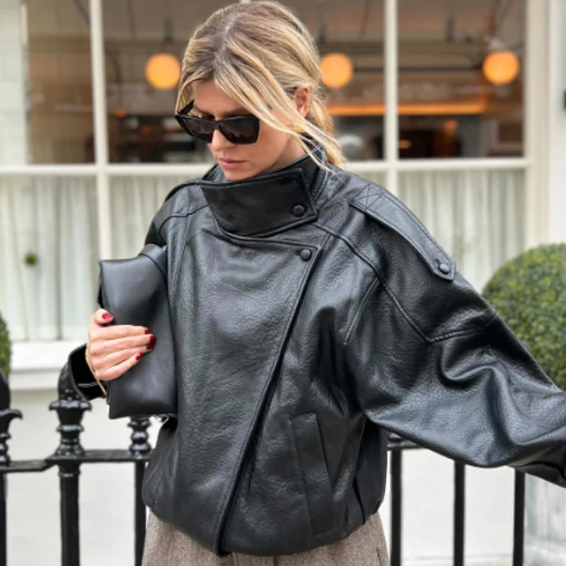Woman wearing a black faux leather jacket with a mock neck.