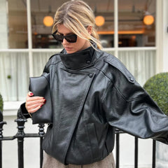 Woman wearing a black faux leather jacket with a mock neck.