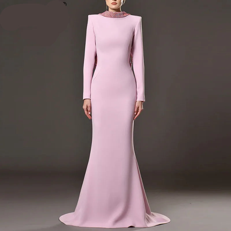 Pink evening gown with long sleeves on a gray background, featuring the brand QMQA.