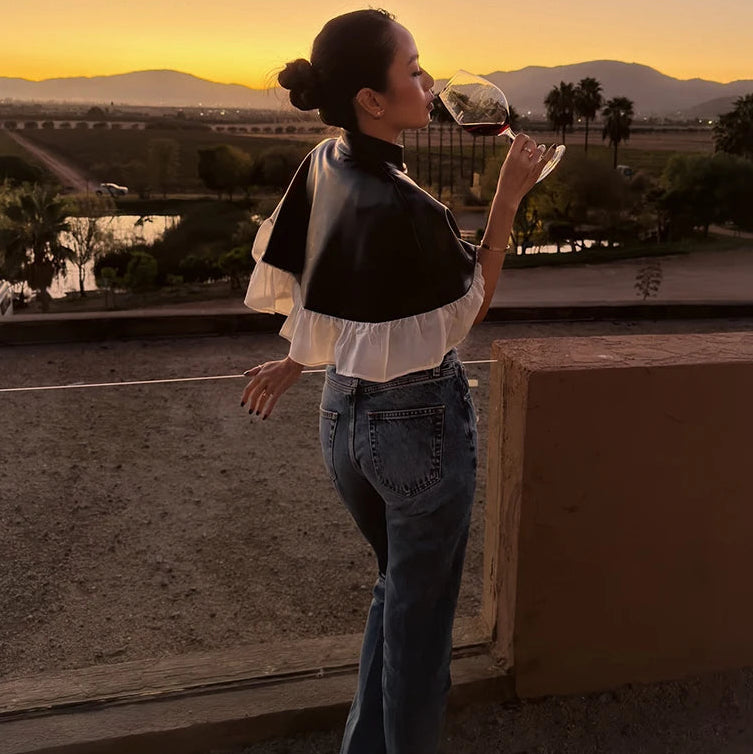 Woman enjoying a glass of wine with a scenic view of mountains and sunset.