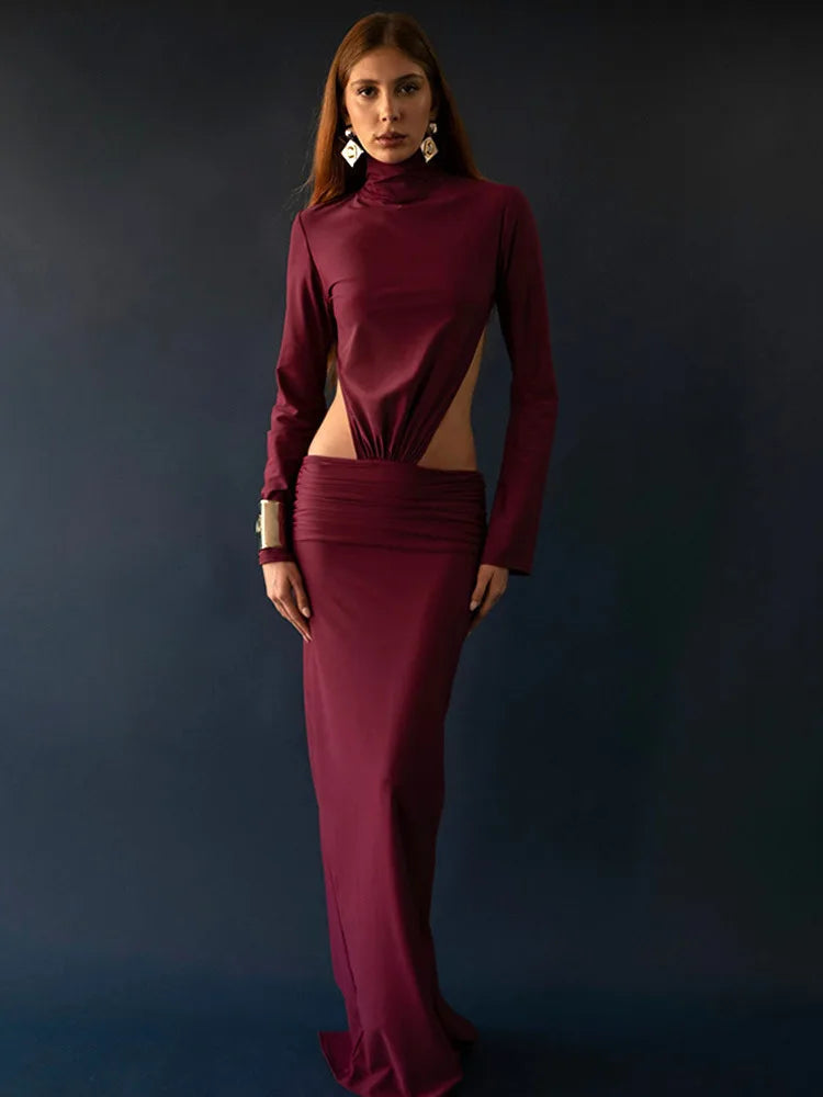 Woman wearing a burgundy dress with cut-out design against a dark background
