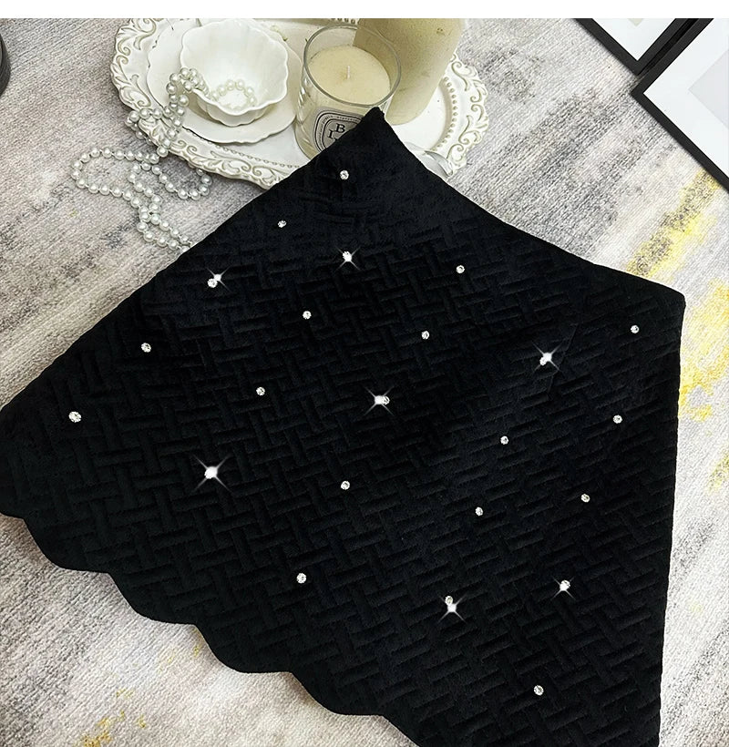 Black textured fabric with white polka dots on a gray surface