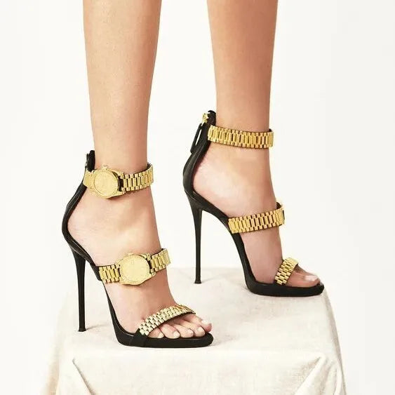 Black dress heels with gold metal watch strap detail on feet
