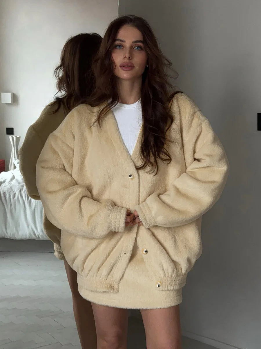 Woman wearing a beige oversized jacket in a minimalistic room.