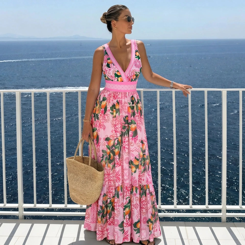 Woman wearing a pink graphic print two-piece swimwear set standing on a balcony overlooking the ocean.
