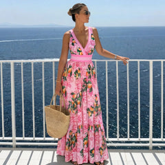 Woman wearing a pink graphic print two-piece swimwear set standing on a balcony overlooking the ocean.