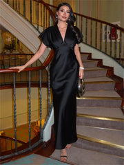 Woman wearing a black flutter sleeve satin maxi dress on stairs