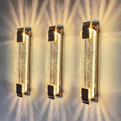 Three decorative wall sconces with crystal accents on a textured wall.