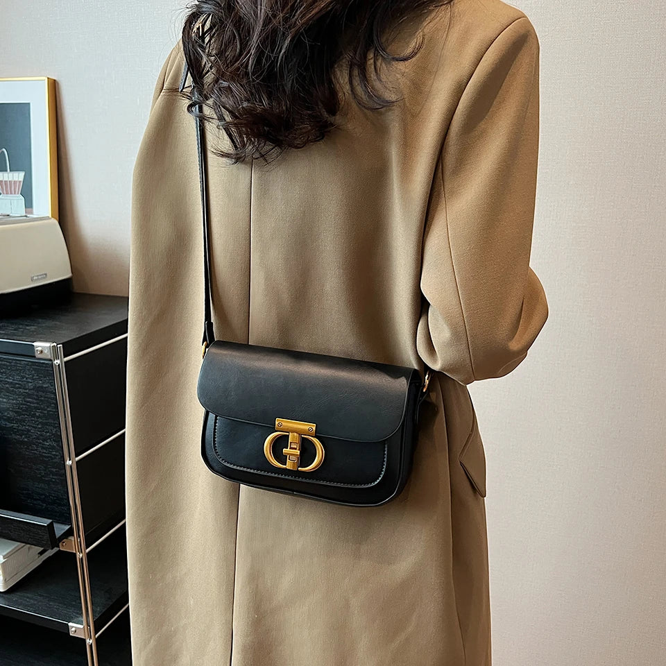 Person wearing a beige coat with a black handbag featuring a gold clasp.