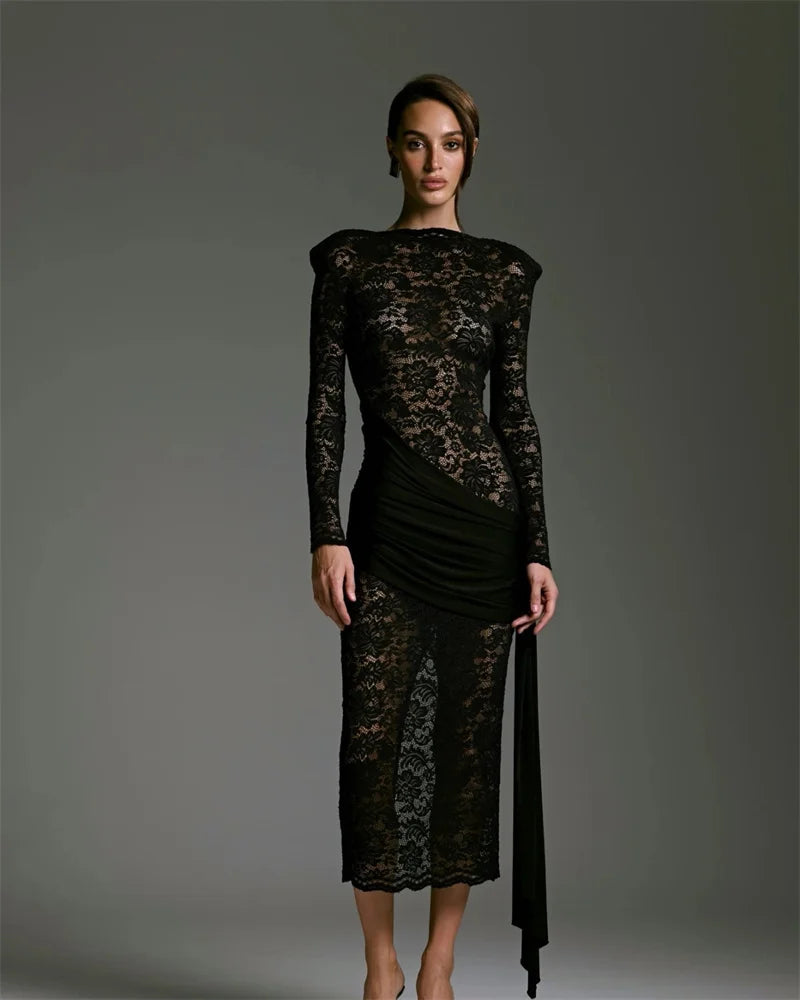 Model wearing a black lace dress against a gray background