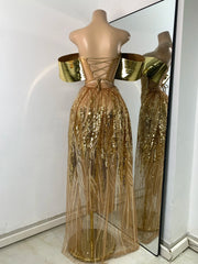 Gold sequin dress on a mannequin with a mirror reflection against a white wall.