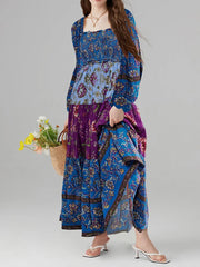 Woman wearing a blue and purple patterned dress holding flowers against a gray background