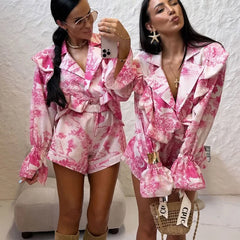 Two women in matching pink floral outfits taking a selfie.