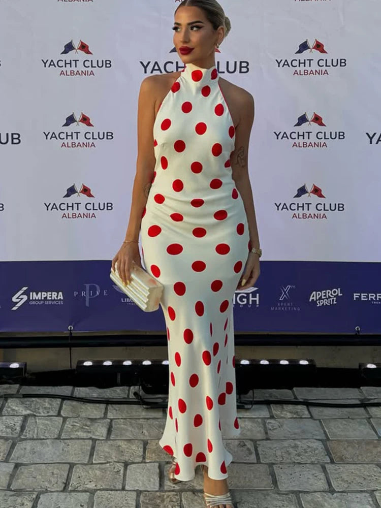 Polka dot halter neck maxi dress posing on a red carpet.