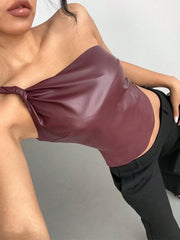 Person wearing a burgundy leather top and black pants on a plain background