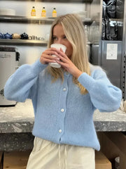 Person wearing a light blue sweater in a kitchen setting