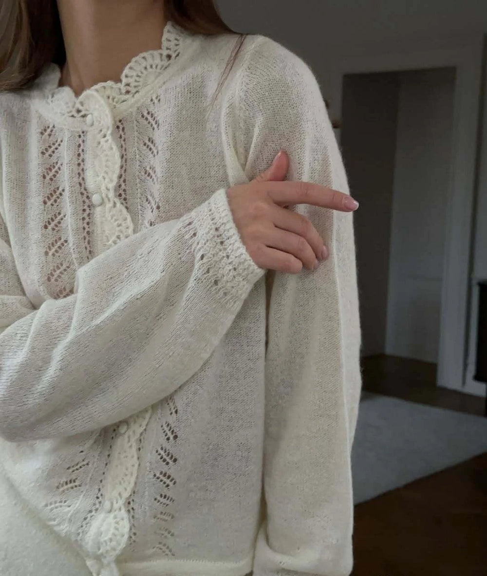 Person wearing a white lace-trimmed sweater in an indoor setting