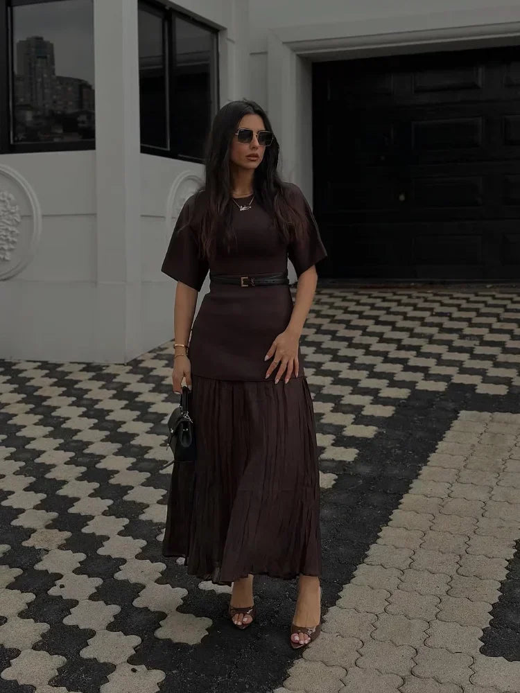 Woman in a brown dress standing on a checkered pavement.