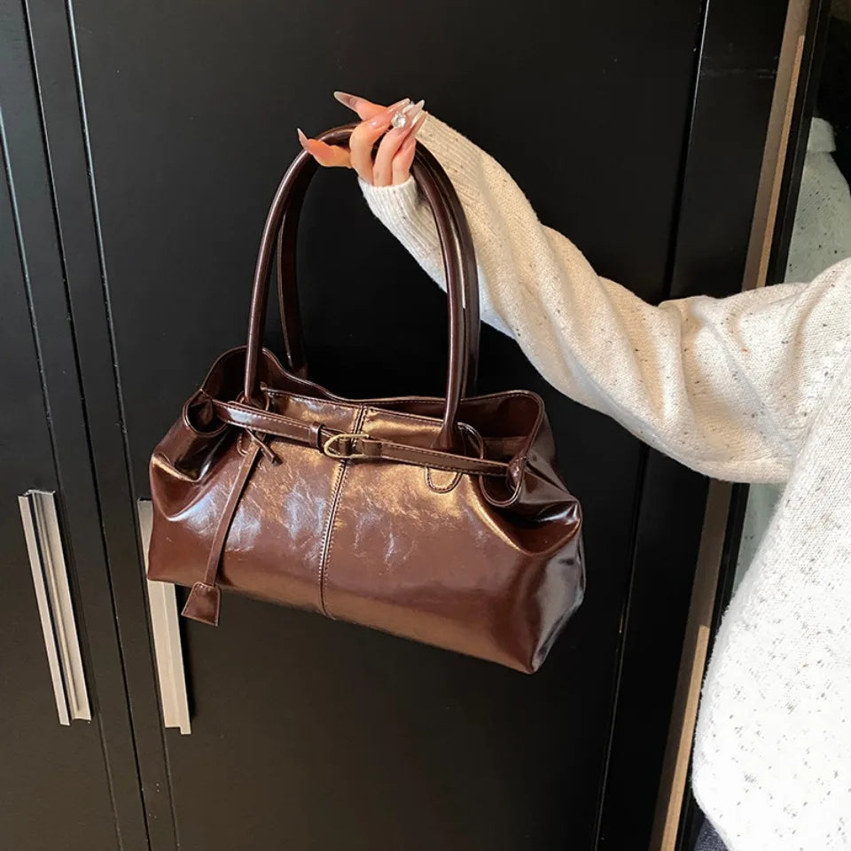 Close-up of glossy faux leather top-handle tote bag