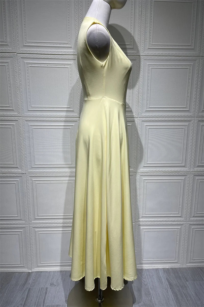 Mannequin wearing a light yellow dress against a white paneled wall.