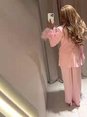 Person wearing a pink outfit with feathered sleeves taking a mirror selfie.