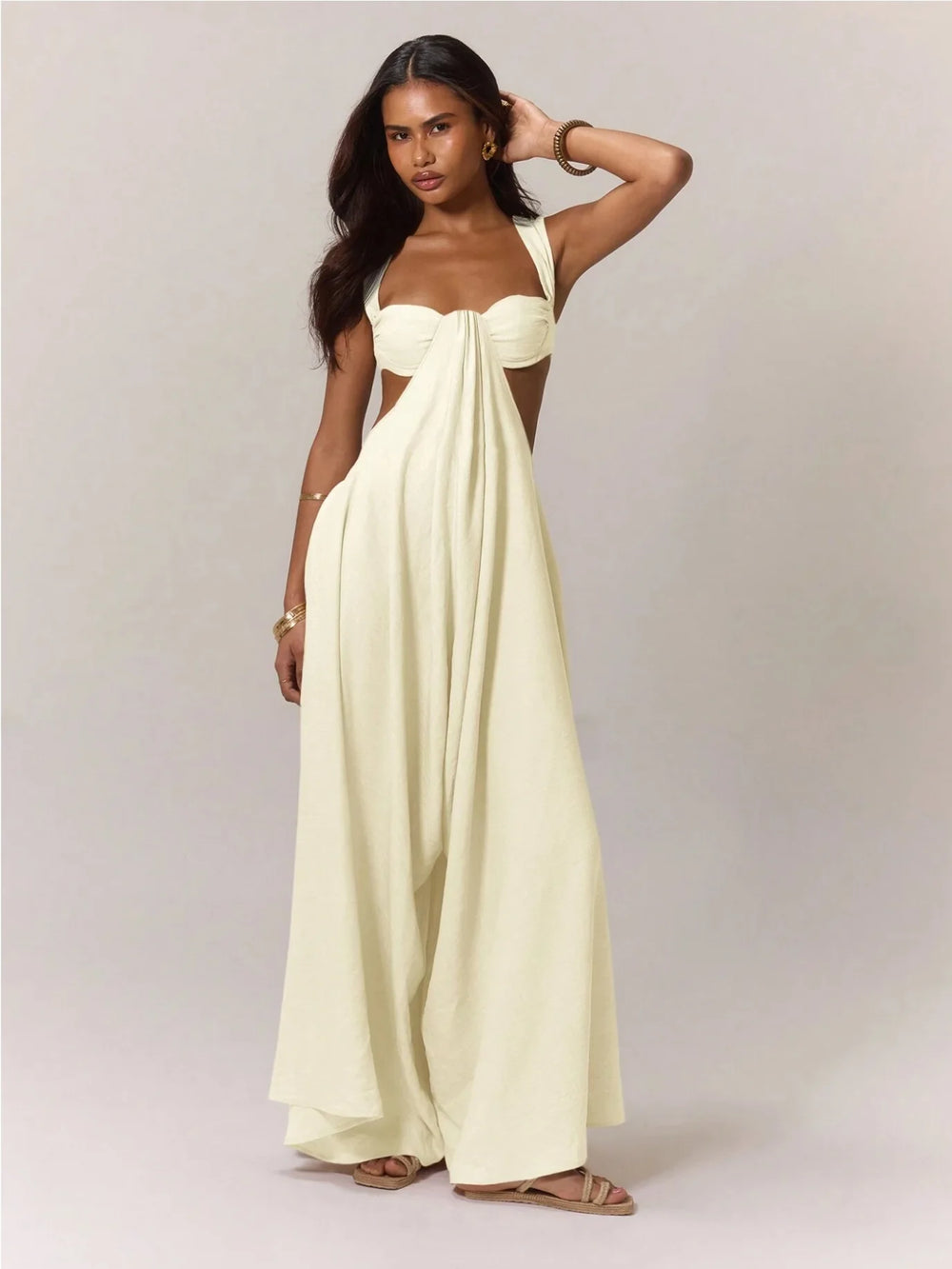 A woman wearing a strapless, long, white jumpsuit against a plain background
