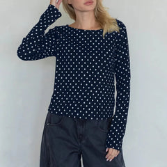 Person wearing a navy blue long-sleeve top with white polka dots against a plain background
