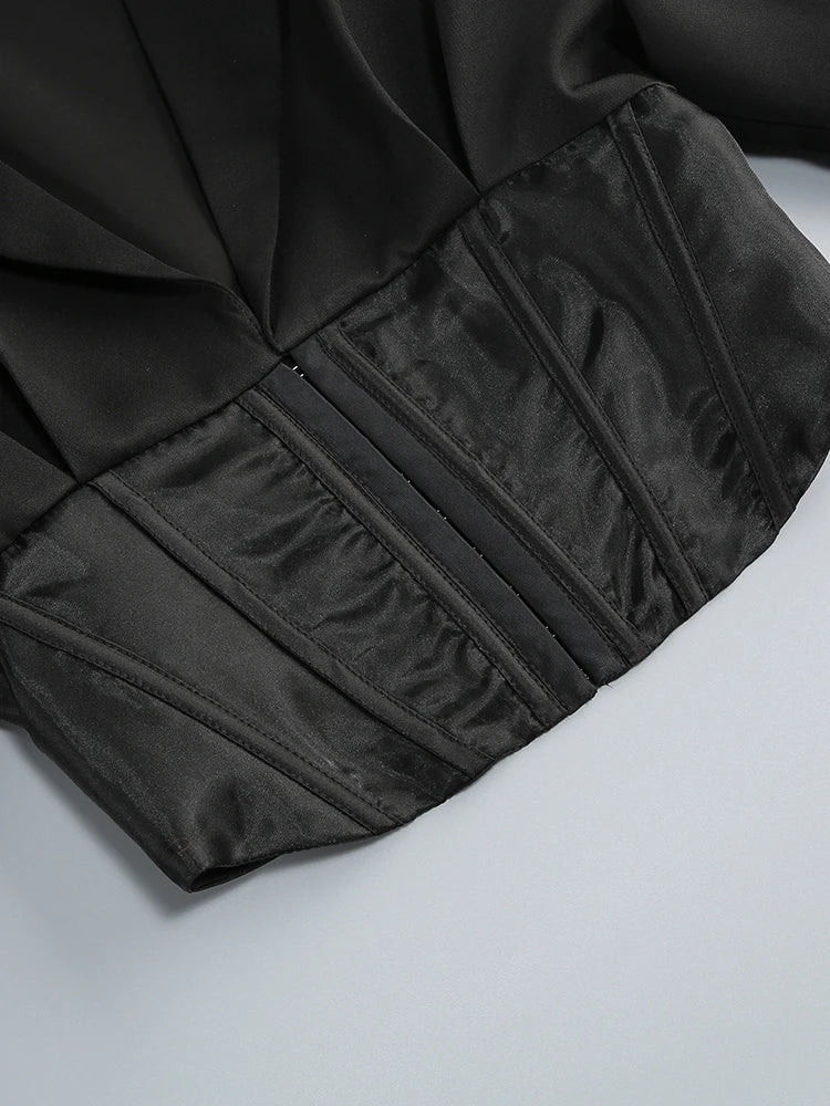 Close-up of a black garment with pleated details on a light gray background