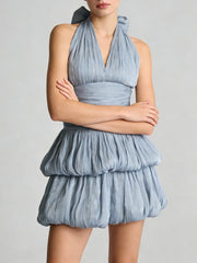 A woman wearing a blue dress with a ruffled skirt on a plain background