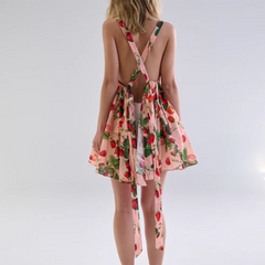Woman wearing a pink floral dress with an open back on a white background