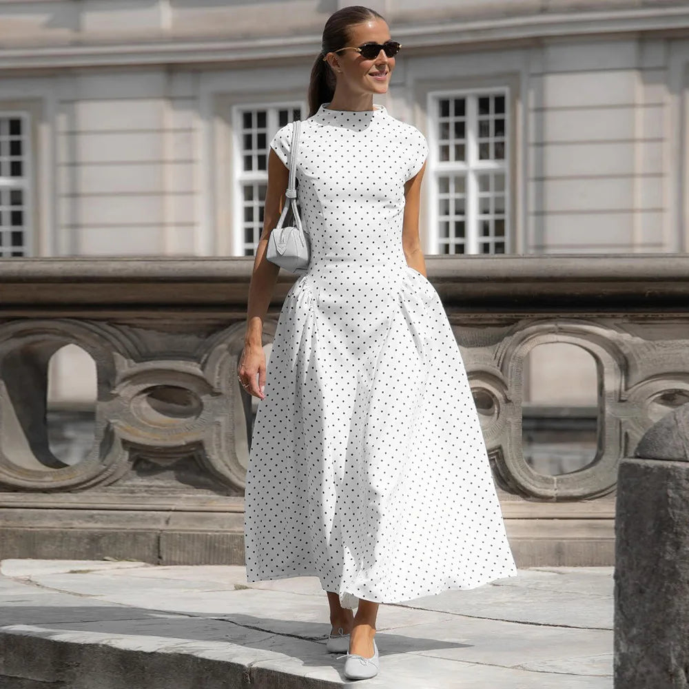 Woman in a white polka dot dress standing in front of a classical building.