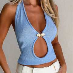 Woman wearing a blue halter top with shell embellishments on a neutral background
