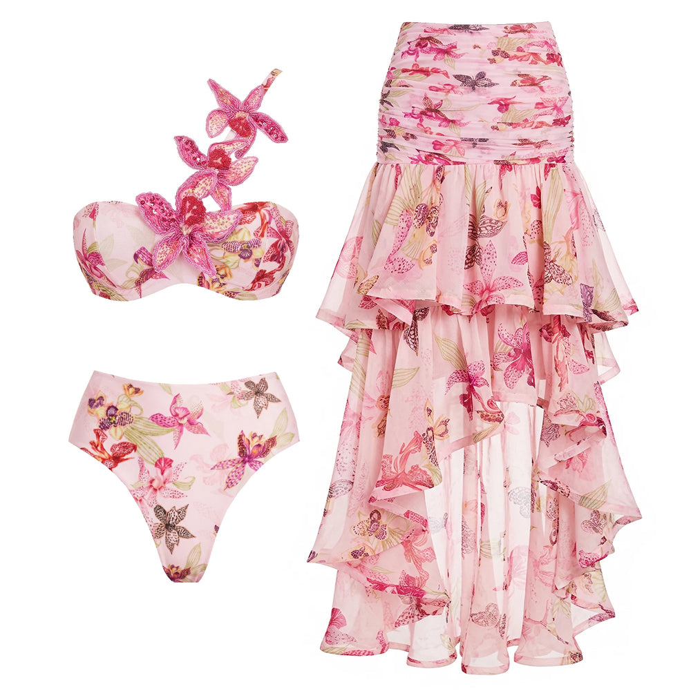 Pink floral print bikini top with floral embellishments and high-waisted bikini bottom, paired with a high-low ruffled skirt.