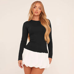 Woman wearing a black long-sleeve top and white skirt on a beige background