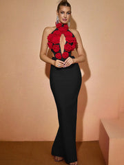 Woman wearing a black dress with red floral embellishments against a beige background