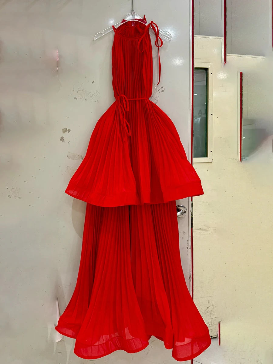 Red evening gown hanging on a rack against a white wall.